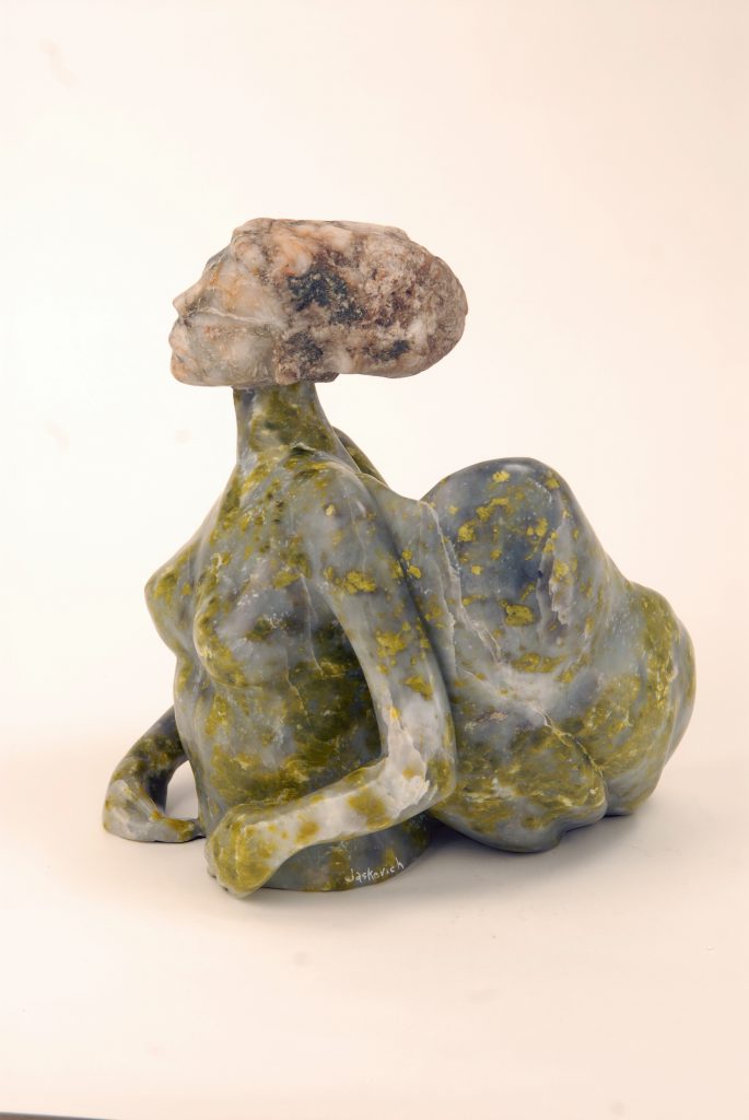 A ceramic sculpture of a woman sitting on the ground.