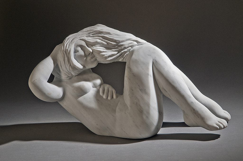 A sculpture of a woman sitting on the ground.